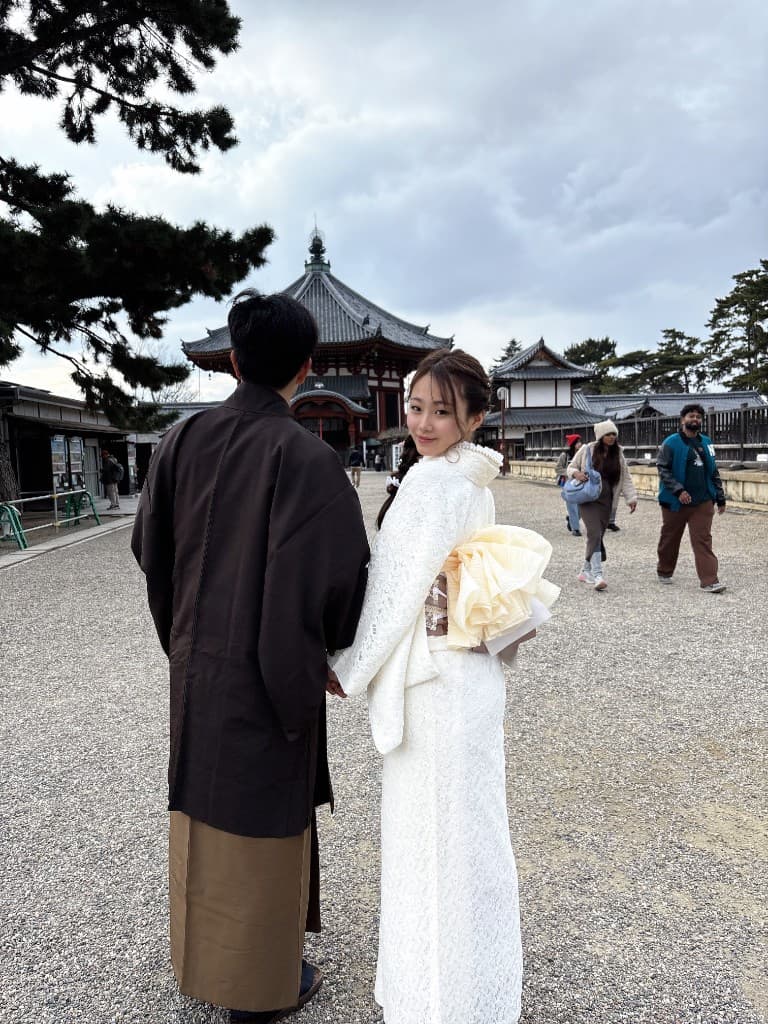 白色レース着物の女性と男性が奈良の寺院前の石畳を歩く