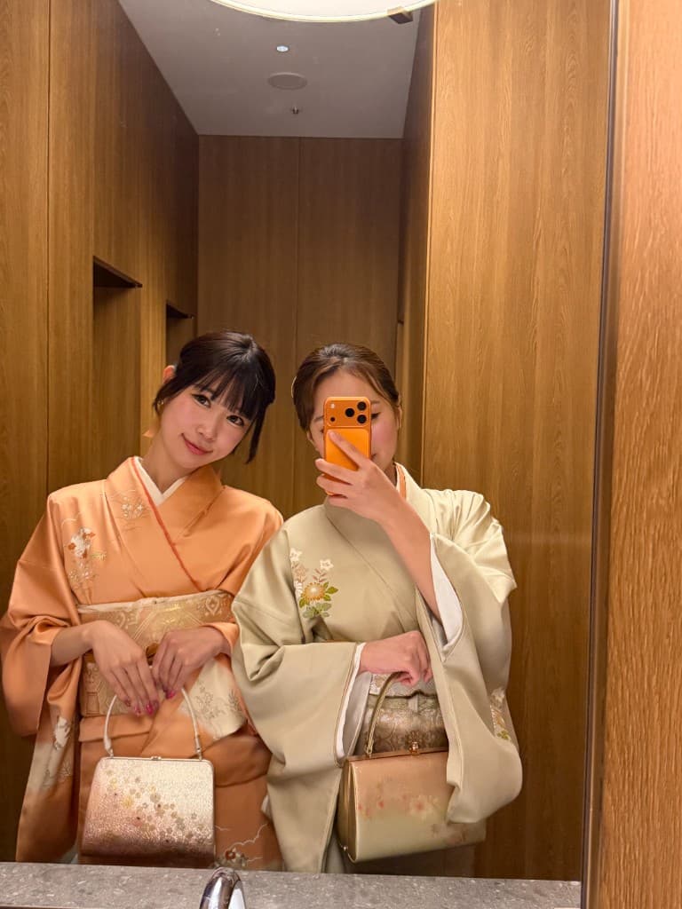 鏡越しに自撮りする、淡色着物のコーディネートをした二人の女性