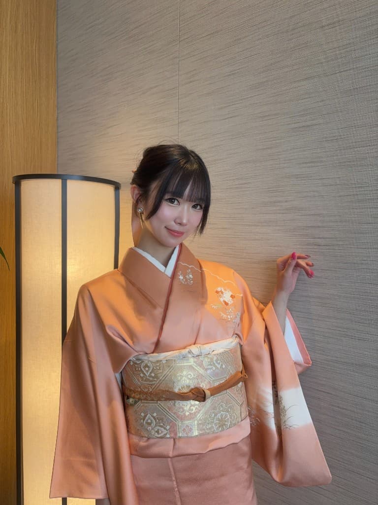 淡色の着物を着た女性が室内で微笑む